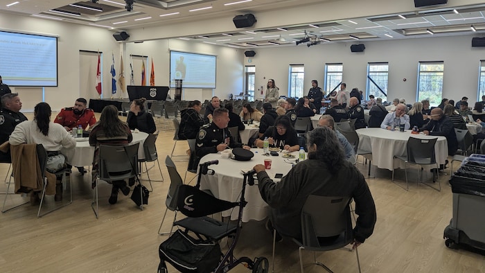 Des gens mangent à plusieurs tables rondes.