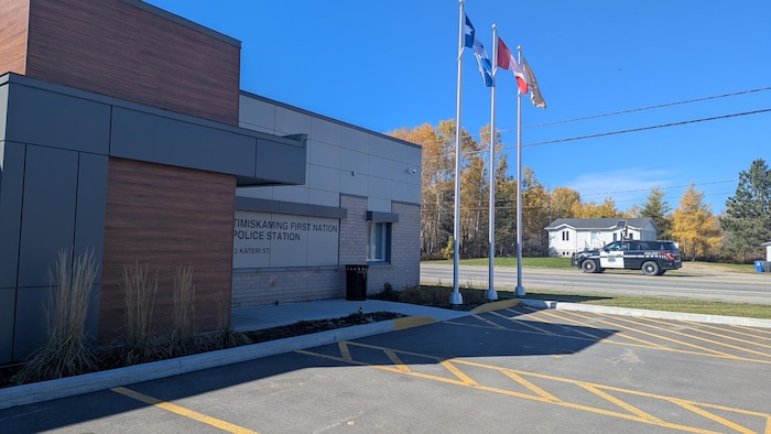 Le bâtiment extérieur du nouveau poste de police avec une voiture de police qui passe sur la route 101 à côté.