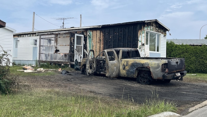 Un véhicule et une maison calcinée dans un quartier résidentiel.