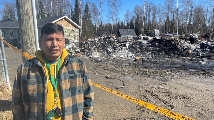 Raynald Papatie pose devant les décombres d'un bâtiment incendié.