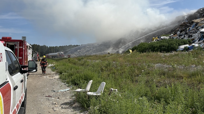 Des pompiers sont mobilisés pour éteindre le feu à l'écocentre. De la fumée s'échappe des débris.