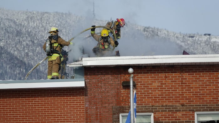 Trois pompiers sur le toit de l'école Bourg de Carleton-sur-Mer.