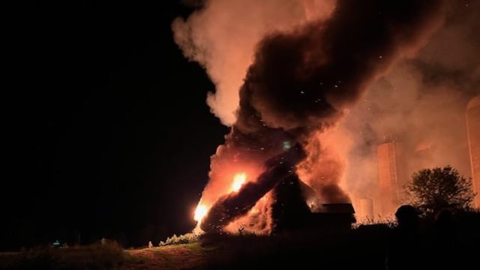 Une ferme enflammée, la nuit.