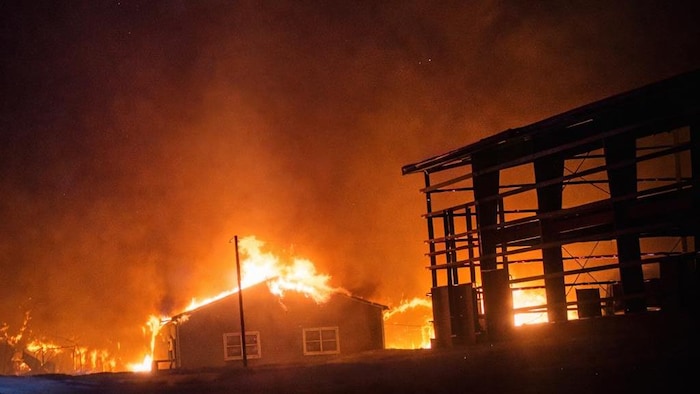 Un bâtiment et une structure avoisinante en feu. 
