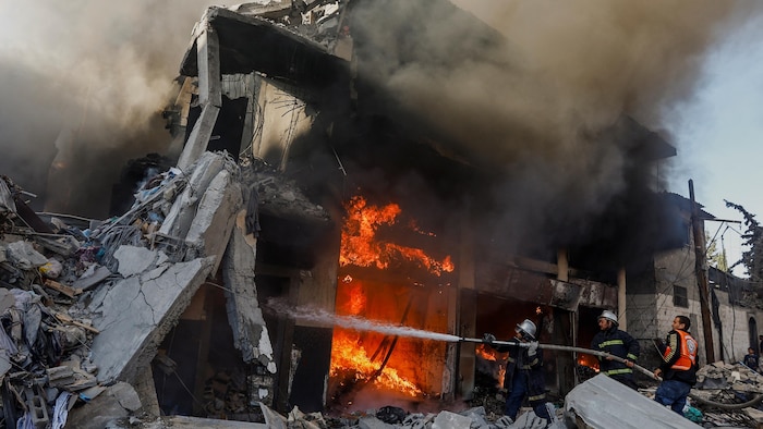 رجال إطفاء فلسطينيون يعملون على إخماد حريق في أنقاض منزل أُصيب في غارة إسرائيلية على مدينة خان يونس جنوبيّ قطاع غزة في 9 كانون الأول (ديسمبر) 2023.