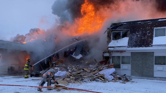 Des pompiers combattent un incendie en arrosant le brasier.