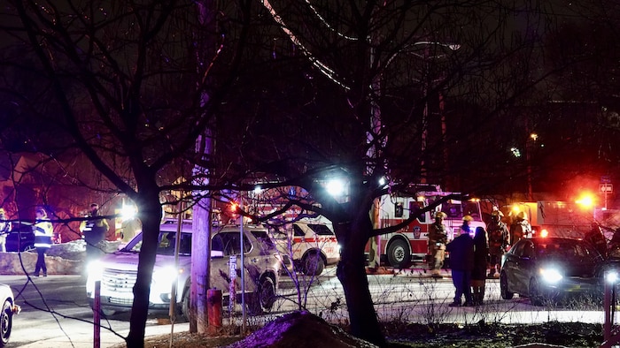 Des pompiers et des policiers sont à l'œuvre tandis que leurs véhicules d'urgences se trouvent dans la rue.