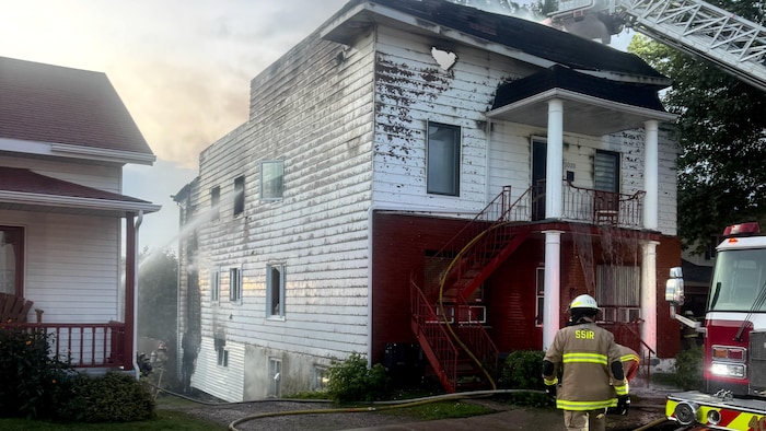 Des pompiers éteignent le feu dans un immeuble du centre-ville de Roberval.