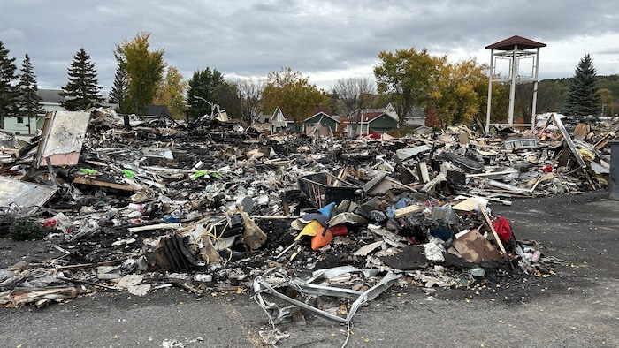 Des débris d'un incendie s'amoncellent au sol.