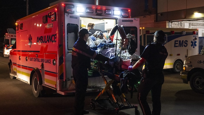 Des ambulanciers font monter une personne blessée dans une ambulance.