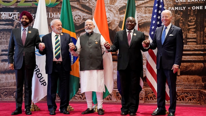 Narendra Modi avec quatre autres chefs d'État et de gouvernement – dont Joe Biden – se tiennent la main devant les drapeaux de leurs pays respectifs.