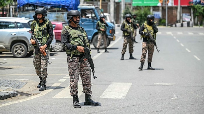 Des hommes en habits militaires patrouillent dans une rue. 