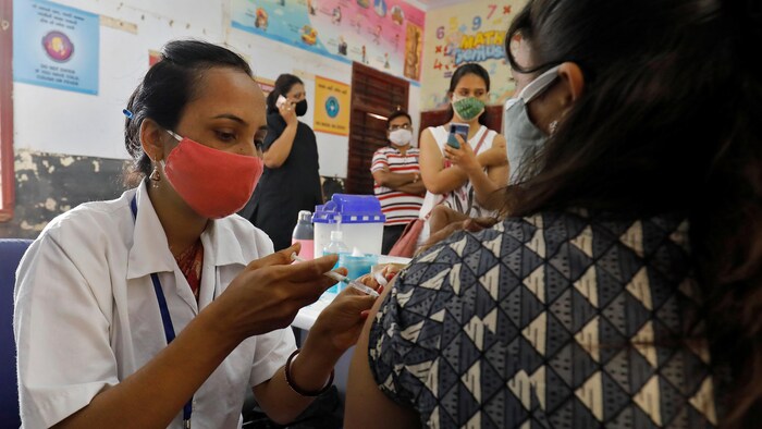 Une infirmière indienne injecte le vaccin de la COVID-19 à une patiente. 