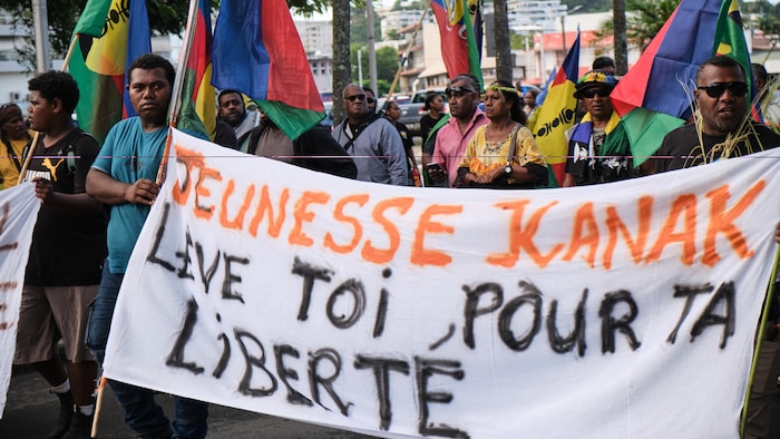 Des indépendantistes tiennent une banderole qui porte la mention « jeunesse kanak, lève-toi pour ta liberté ».
