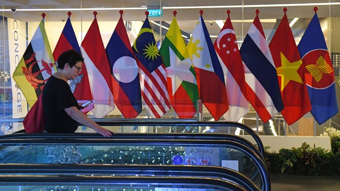 Une femme passe devant les drapeaux nationaux de l'Association des nations de l'Asie du Sud-Est. 