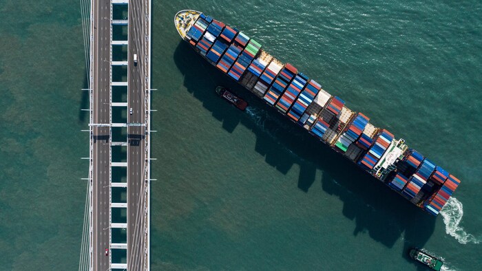 Cette photo aérienne montre un porte-conteneurs naviguant sous un pont à Hong Kong.