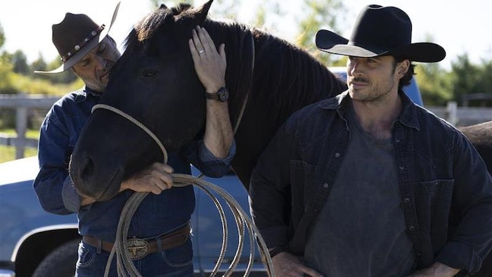 Deux hommes sont à côté d'un cheval. 