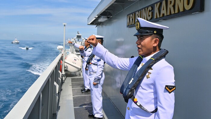 Des militaires indonésiens se tiennent debout, le poing levé, sur un bateau militaire.