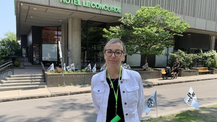 Une dame pose &agrave; l'ext&eacute;rieur et devant un h&ocirc;tel.