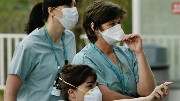 Des infirmières portent de l'équipement de protection contre le SRAS pendant qu'elles marchent à l'extérieur d'un hôpital de Toronto en 2003.