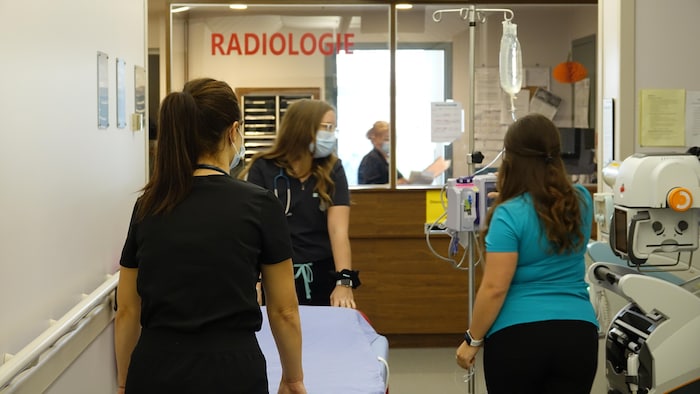 Des infirmières transportent une civière et un soluté dans le service de radiologie de l'hôpital des Îles-de-la-Madeleine.