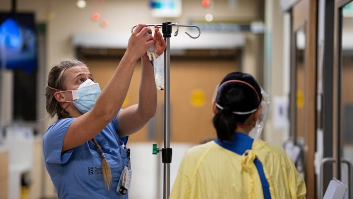 ممرضة بالزي الأزرق وعاملة صحية أُخرى بالزي الأصفر داخل مستشفى.