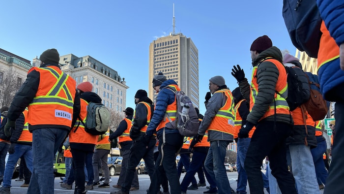 Des ingénieurs vêtus de vestes réfléchissantes manifestent au centre-ville de Québec à l’automne 2024.