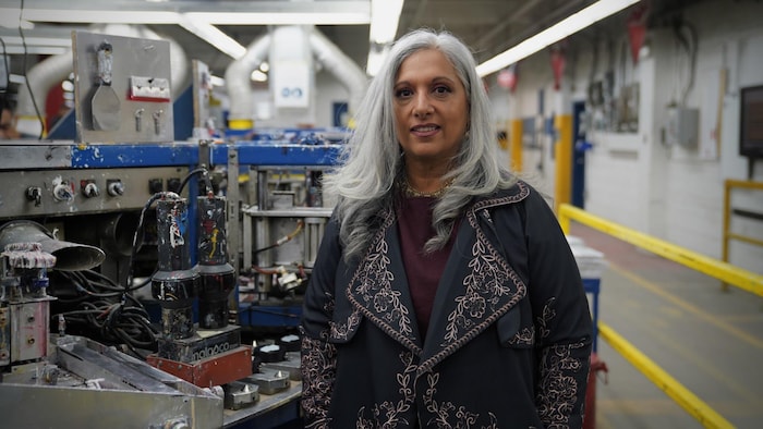 Elle est dans l'usine, près de machines.