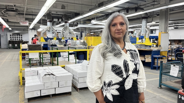 Anita Chandan se tient debout dans l'usine et regarde la caméra.