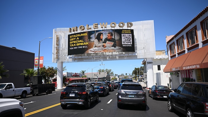 Des automobilistes coincés dans un embouteillage dans le quartier Inglewood passent sous une pancarte publicitaire qui dénonce l'allègement fiscal dont bénéficient les stades qui ont récemment ouvert dans la région.