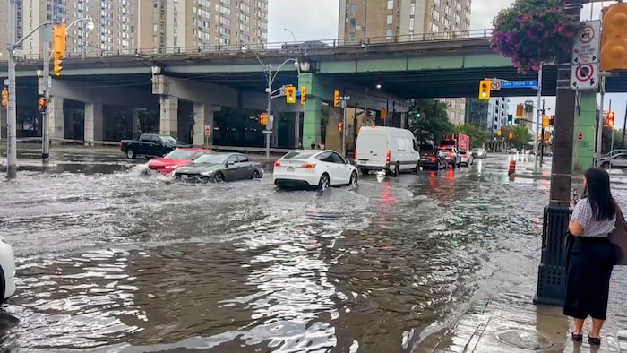 Des voitures tentant de passer dans une intersection inondée à Toronto le 2 septembre 2026. 