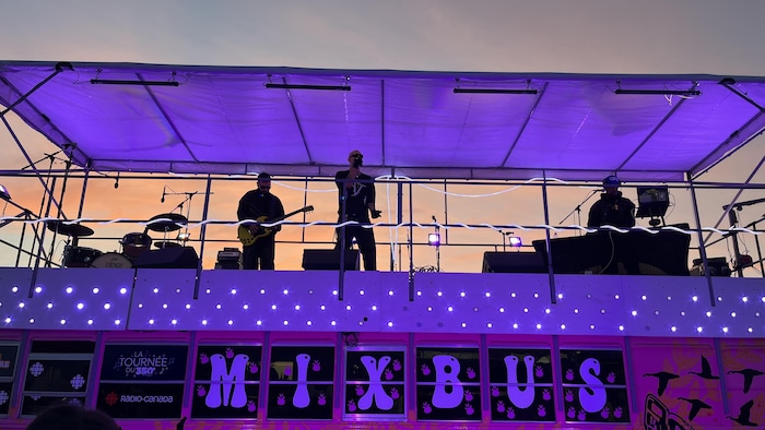 Un groupe de musique en spectacle sur le toit d'un autobus décoré.