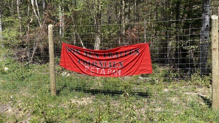 Une banderole rouge sur une clôture en forêt.