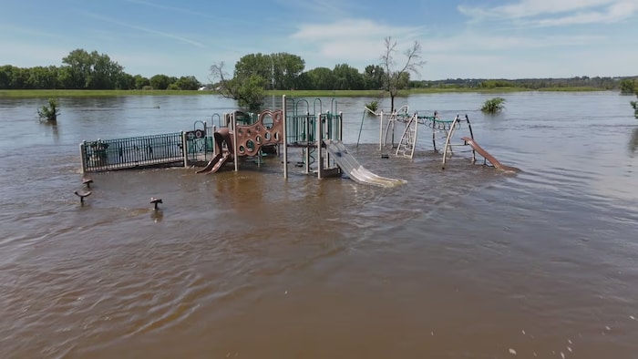 La crue de la rivière Assiniboine entoure une structure de jeux dans le parc Dinsdale de Brandon, le 12 juillet 2026.