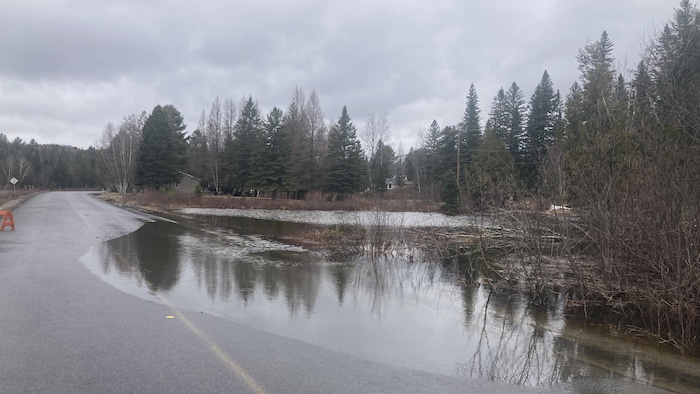 Une route est à moitié inondée par l'eau de la rivière adjacente.