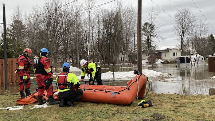 Quatre pompiers gonflent un bateau. 