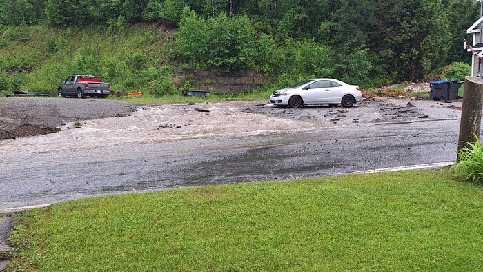 UNe voiture stationnée sur le bord d'une route inondée.