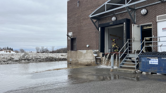 Des boyaux de pompiers qui vident l'eau d'une usine de filtration.