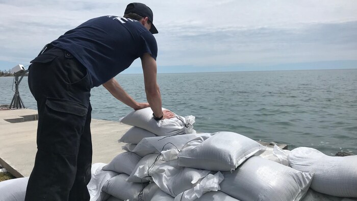 Un homme installe des sacs de sable en bordure du lac Ontario.