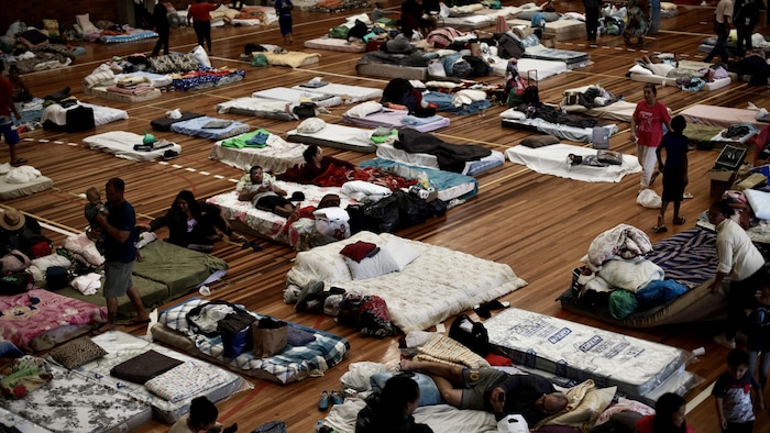 Des dizaines de matelas dans un gymnase.