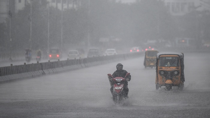 Des usagers circulent sur une route sous des pluies torrentielles