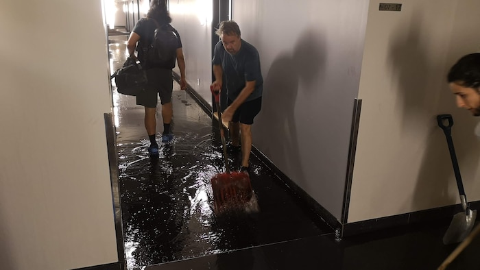 Des résidents pellettent de l'eau pour la sortir de l'immeuble.