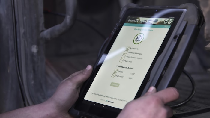 Un individu tient dans ses mains une tablette électronique sur laquelle apparaissent des options de programmation et le mot Ontario.