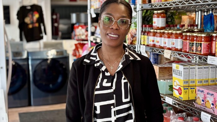 Une femme debout dans une épicerie sourit à la caméra.
