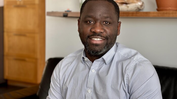 Un homme assis sourit à la caméra.