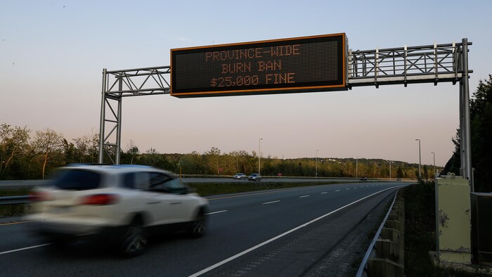 Un babillard électronique au-dessus d'une autoroute. Son message indique que l'amende pour allumer un feu est de 25 000 dollars.