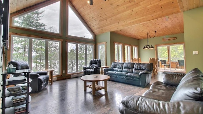 Le salon et la salle à manger du chalet avec de grandes baies vitrées.