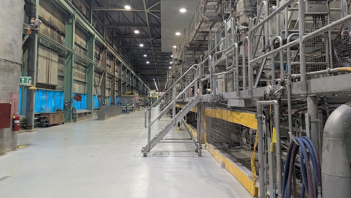 Une grande allée dans un bâtiment industriel avec de la machinerie.