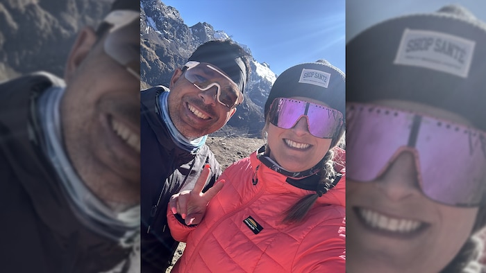 Deux adultes sourient devant un paysage de montagne.