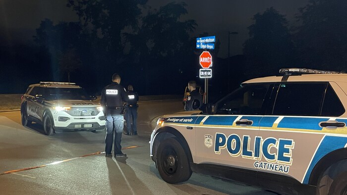 Des policiers de la Ville de Gatineau dehors, autour de leurs véhicules, lors d'une intervention.